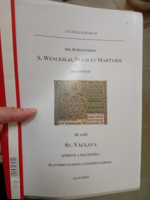 červené desky se svatováclavským oficiem, titulní stránka; v pozadí patka sloupu z krypty sv. Kosmy a Damiána